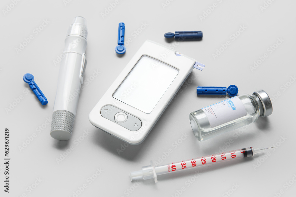 Glucometer with lancet pen, insulin and syringe on grey background. Diabetes concept Glucometer with lancet pen, insulin and syringe on grey background. Diabetes concept