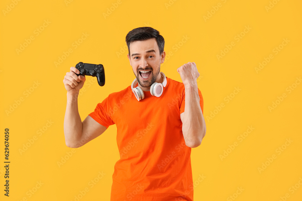 Handsome man with game pad on yellow background Handsome man with game pad on yellow background