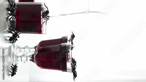 Red drink, like blood in glass goblets on a table with crawling spiders. Congratulations on Halloween. Drink for a masquerade. Spiders, blood, skull halloween party symbol. traditional celebration photo