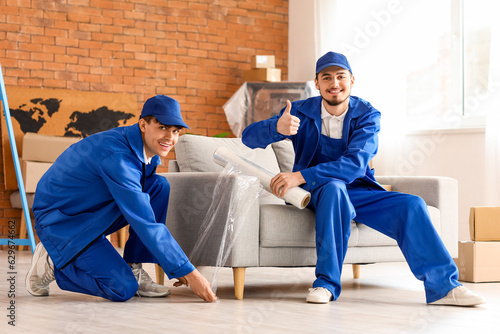 Male movers wrapping sofa w...