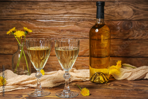 Bottle and glasses of dandelion wine on wooden table