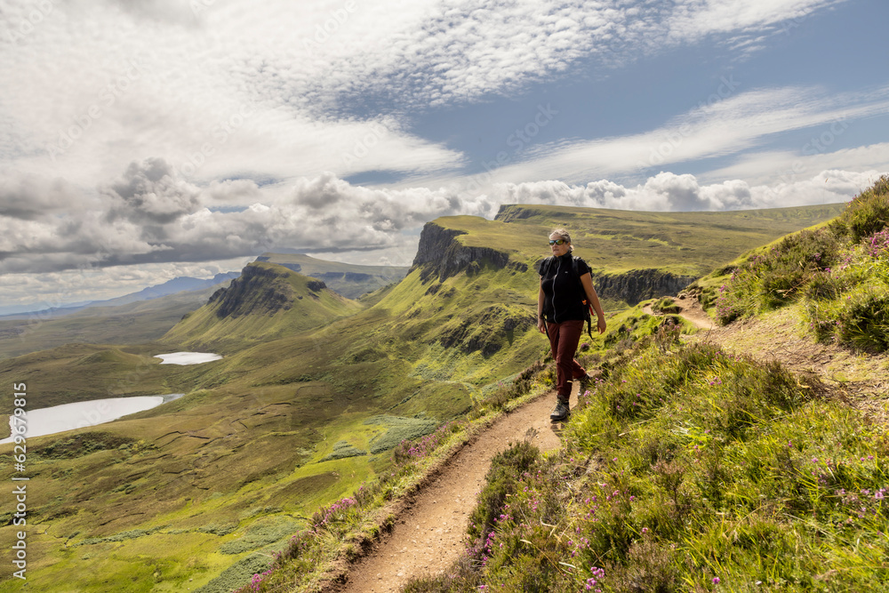 woman hiking on mountain range Quiraing. It is a geological formation on the Scottish Isle of Skye and a hiker's paradise