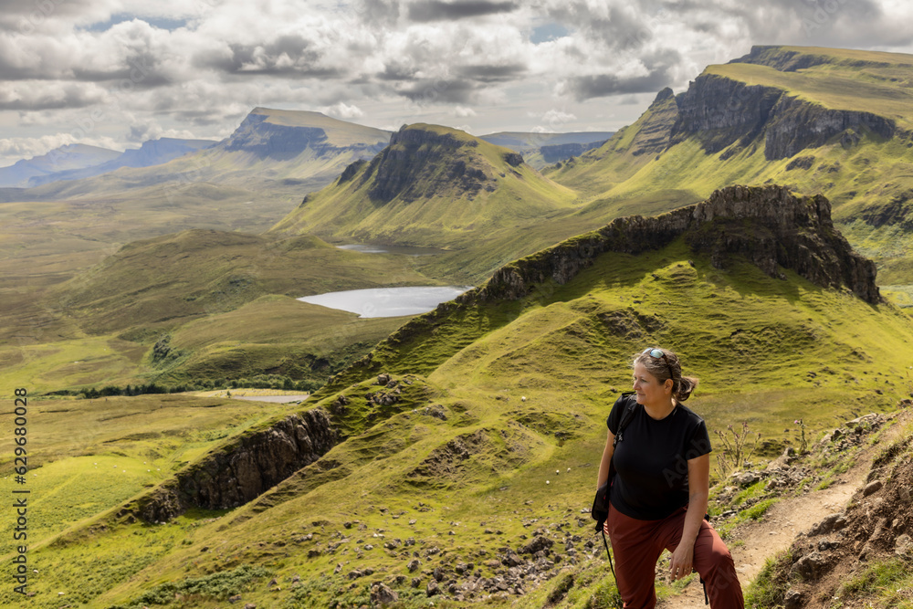 woman hiking on mountain range Quiraing. It is a geological formation on the Scottish Isle of Skye and a hiker's paradise