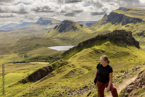  woman hiking on mountain range Quiraing. It is a geological formation on the Scottish Isle of Skye and a hiker's paradise