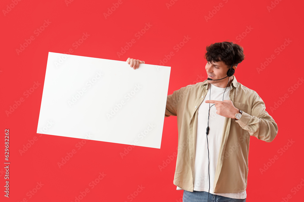 Male technical support agent with blank poster on red background Male technical support agent with blank poster on red background