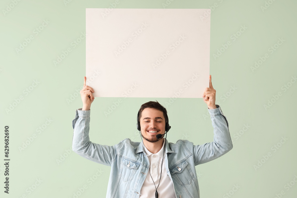 Male technical support agent with blank poster on mint background Male technical support agent with blank poster on mint background