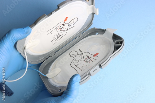 Defibrillator electrodes in the case beeing opened in a light blue background by a professional wearing gloves  photo