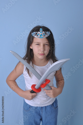 menina criança  luta com espadas de brinquedo em fundo azul, luta divertida  photo