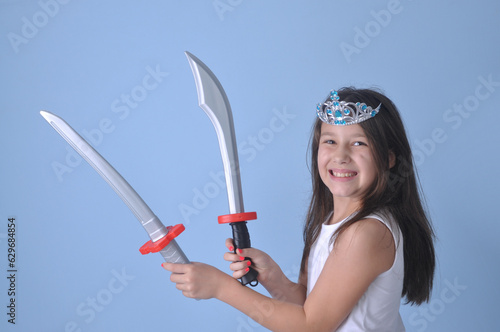 menina criança  luta com espadas de brinquedo em fundo azul, luta divertida  photo