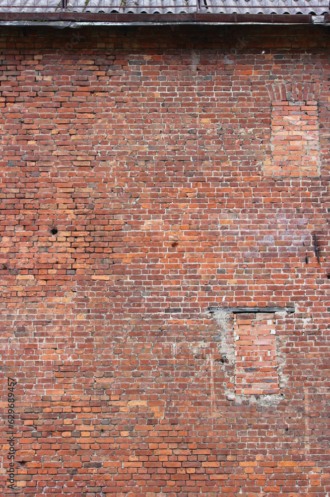 A vertical photo of an old brick wall with a bricked up window. Ancient structure in the historic district of the city A vertical photo of an old brick wall with a bricked up window. Ancient structure in the historic district of the city