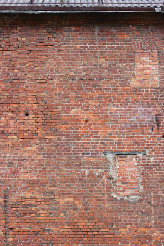 A vertical photo of an old brick wall with a bricked up window. Ancient structure in the historic district of the city