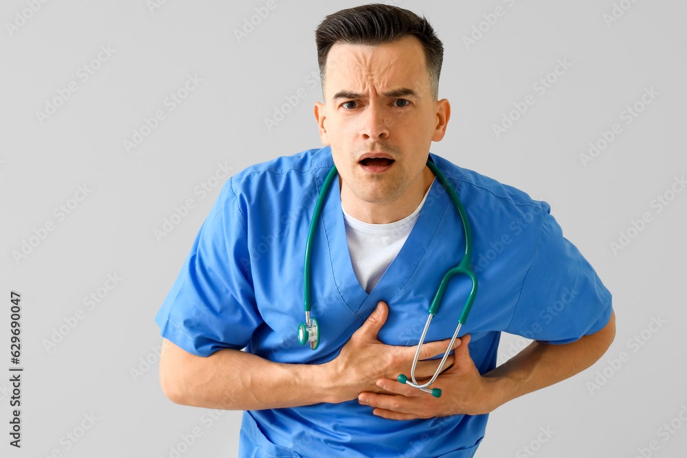 Male doctor having heart attack on light background Male doctor having heart attack on light background