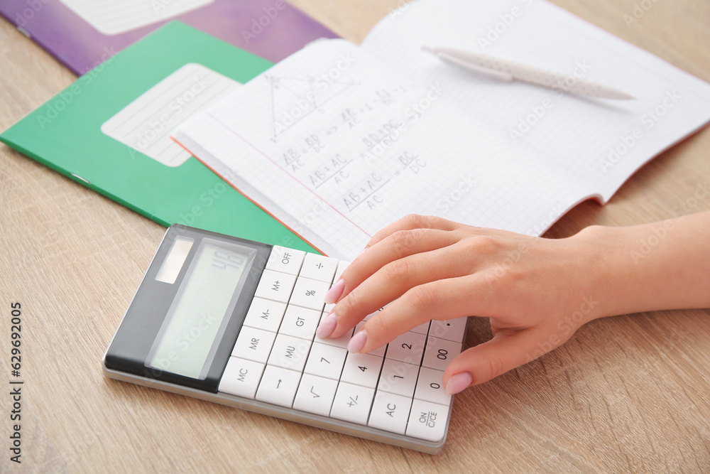 Woman working with calculator on wooden table, closeup Woman working with calculator on wooden table, closeup