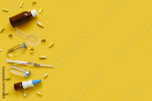 Pills, syringe and ampules on yellow background