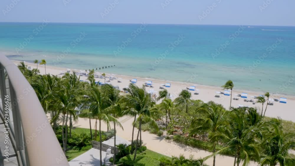 Captivating view from terrace of high-rise apartments in splendid resort in Miami. Tropical beach with exotic palm trees, crystal clear water of Atlantic ocean and white sand
