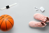 Pair of sneakers, ball for playing basketball and modern gadgets on light background