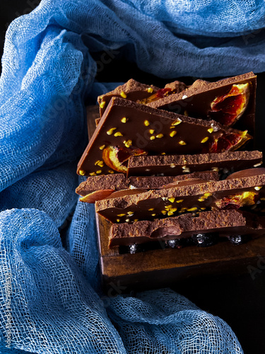 Pieces of chocolate with nuts and raisins on a dark background