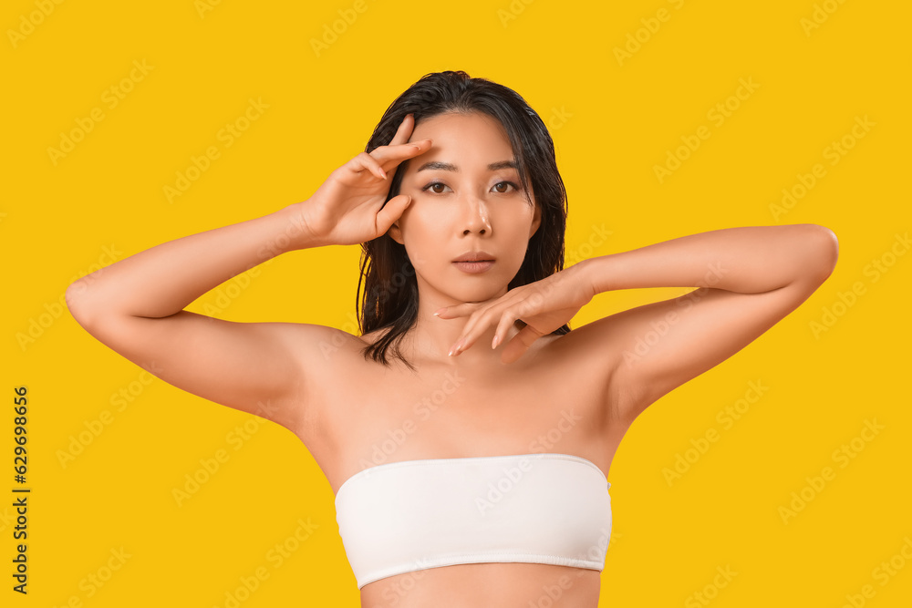 Fototapeta premium Beautiful young Asian woman with healthy skin on yellow background
