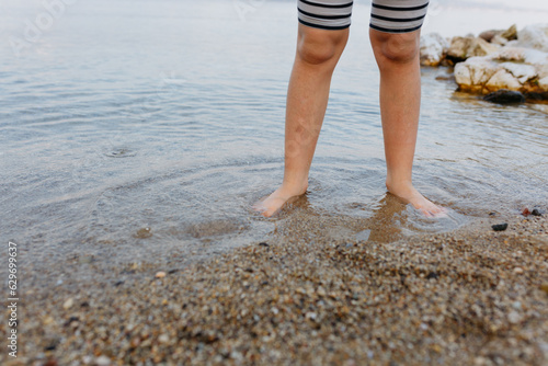 barefeet child legs standing in the water in stone beach © Victoria