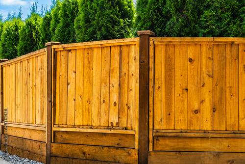 Beautiful new wooden fence around the house. Wooden fence with trees around. Solid Cedar fence.
