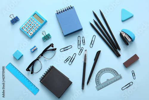 Different school stationery, notebooks and glasses on blue background