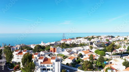 Aerial footage of the beautiful town of Albufeira in Portugal, showing the Praia de Albufeira and Praia da Oura Beach in the background, on a clear sunny blue sky day in the summer time. photo