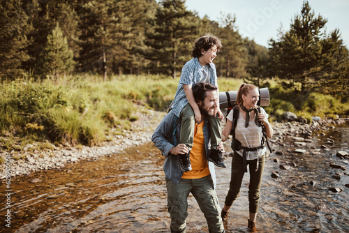 Young family hiking in the forest and crossing a creek together photo