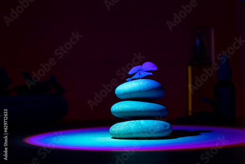 Stack of pebbles with flower, relax calm concept. Ultraviolet background.