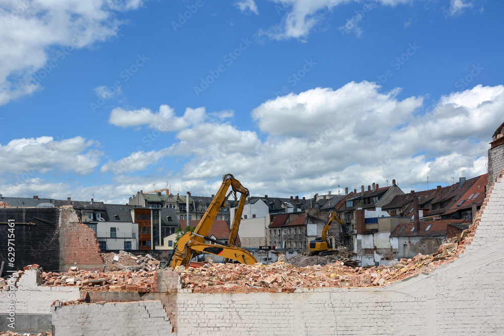 Several construction excavators are engaged in dismantling an old house. Dismantling the city's housing stock for renovation Several construction excavators are engaged in dismantling an old house. Dismantling the city's housing stock for renovation