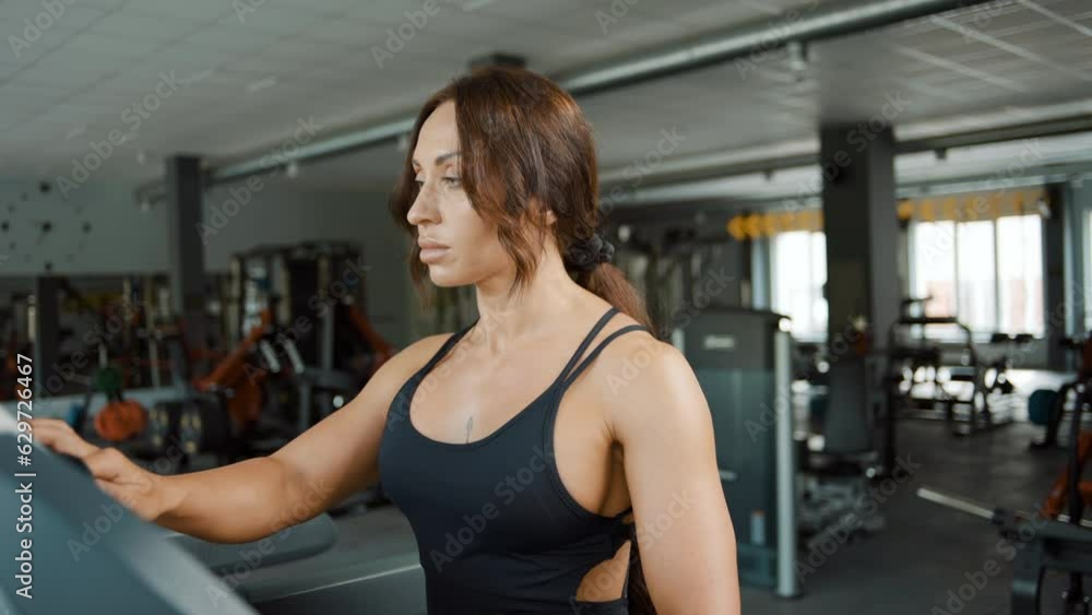 Young athletic beautiful woman training on a treadmill in the gym. Slow motion Young athletic beautiful woman training on a treadmill in the gym. Slow motion
