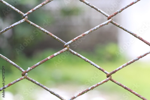 selective focus of Old rust wire fence. Hole in the fence. with diamond pattern