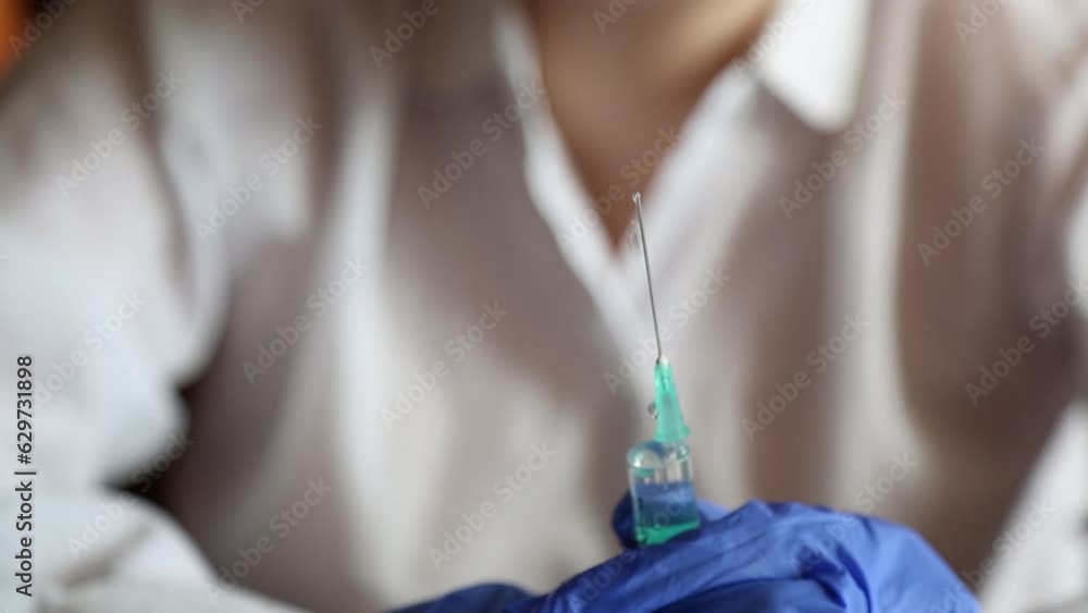 A medical worker holds a syringe with medicine in his hands in medical gloves. The doctor squeezes a stream of liquid out of the syringe. The nurse prepares the syringe for injection. A medical worker holds a syringe with medicine in his hands in medical gloves. The doctor squeezes a stream of liquid out of the syringe. The nurse prepares the syringe for injection.