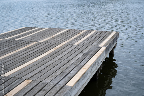 Aged and renovated wooden pier dock on lake. Surface of a wooden pier made of planks with cracks