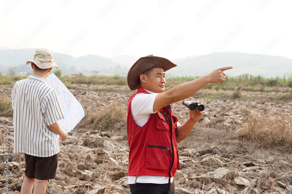 Asian man explorer wears hat, red vest shirt, holds binocular to ...