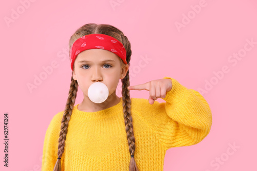 Girl blowing bubble gum on pink background