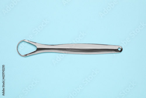 Metal tongue cleaner on light blue background, top view