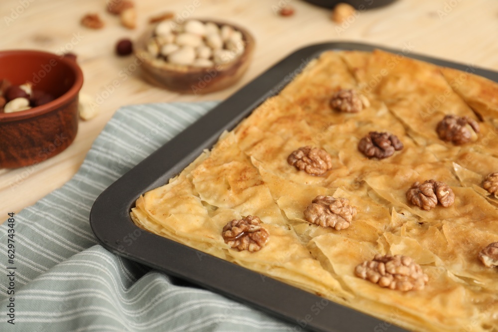 Delicious baklava with walnuts in baking pan on table, closeup