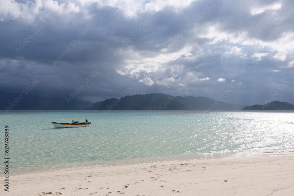 Solo motorboat in beautiful shallow tropical water with rain storm in the distance on a remote island in Papua New Guinea Solo motorboat in beautiful shallow tropical water with rain storm in the distance on a remote island in Papua New Guinea