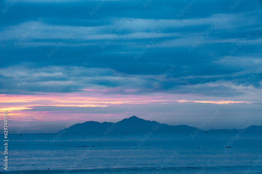 Seascape, cloudy sky and island at dawn.