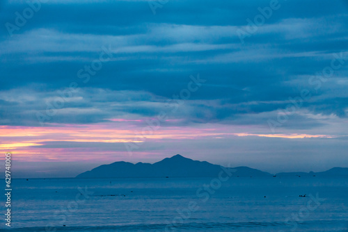 Seascape, cloudy sky and island at dawn.