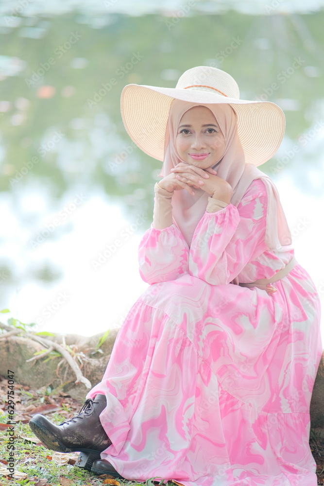 Portrait of beautiful young Muslim girl wearing Hijab and Jubah dress in outdoor scenes holding camera. Stylish Muslim female hijab fashion lifestyle portraiture concept.
