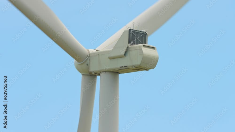 Large wind turbines with blades in the farming fields area, below view. Blue sky. Sustainable alternative energy. Slow movement. Windmills at the farm, generating green energy. Large wind turbines with blades in the farming fields area, below view. Blue sky. Sustainable alternative energy. Slow movement. Windmills at the farm, generating green energy.