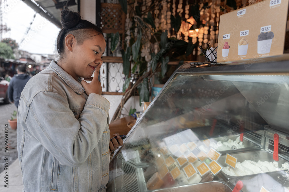 A young Hispanic woman is thinking while choosing an ice cream A young Hispanic woman is thinking while choosing an ice cream