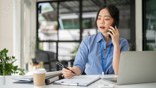 A beautiful Asian businesswoman is talking on the phone, dealing business over the phone