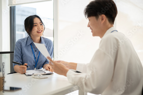Wallpaper Mural A happy Asian female office worker is discussing work, brainstorming with a male colleague Torontodigital.ca