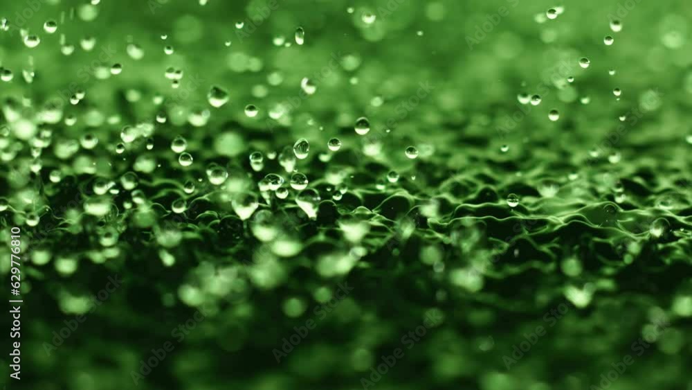 Macro close up super slow motion 1000 fps. Splash drops liquid in green color. Splashes water drops liquid when surface water is vibration. Wave and drops in green background. Harmony meditative shot Macro close up super slow motion 1000 fps. Splash drops liquid in green color. Splashes water drops liquid when surface water is vibration. Wave and drops in green background. Harmony meditative shot
