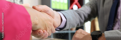 Close-up of two business people shaking hands at office table.