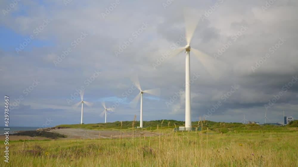 Wind farm spinning and storm clouds gathering with sunlit pools moving across landscape. Time lapse 30x. Wind farm spinning and storm clouds gathering with sunlit pools moving across landscape. Time lapse 30x.