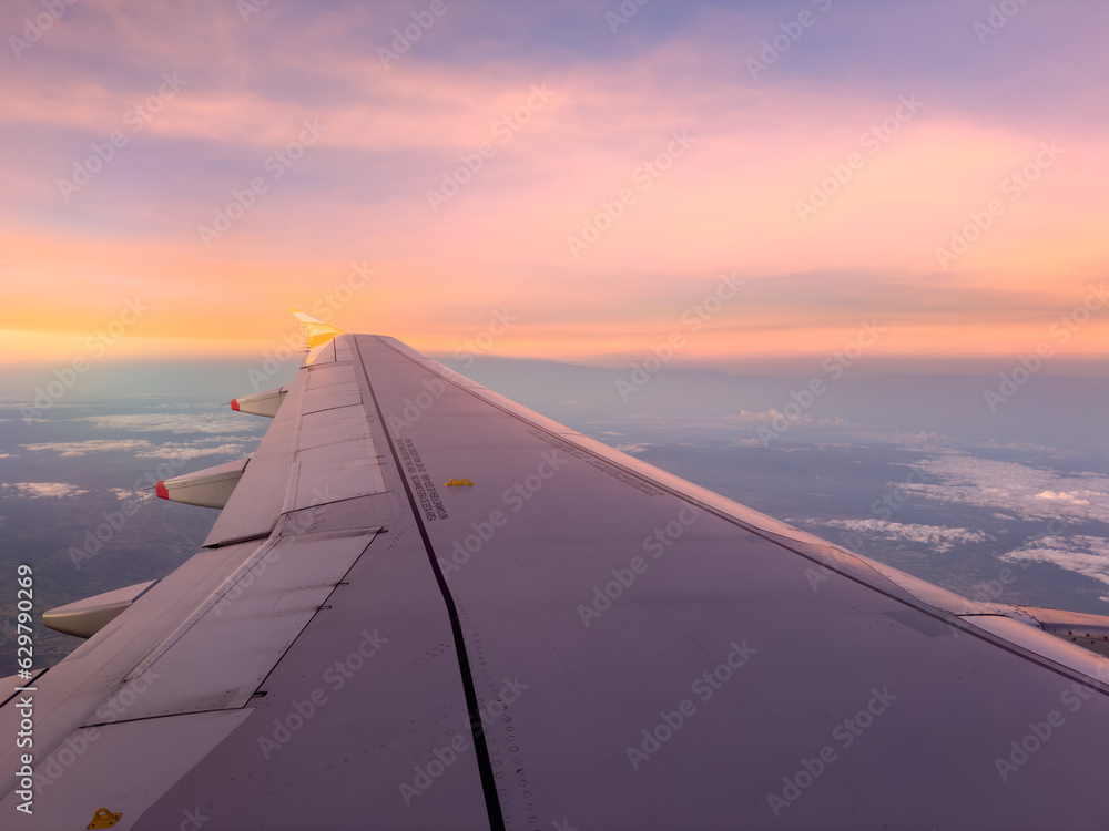 Airplane wing with sunset light while flying at altitude