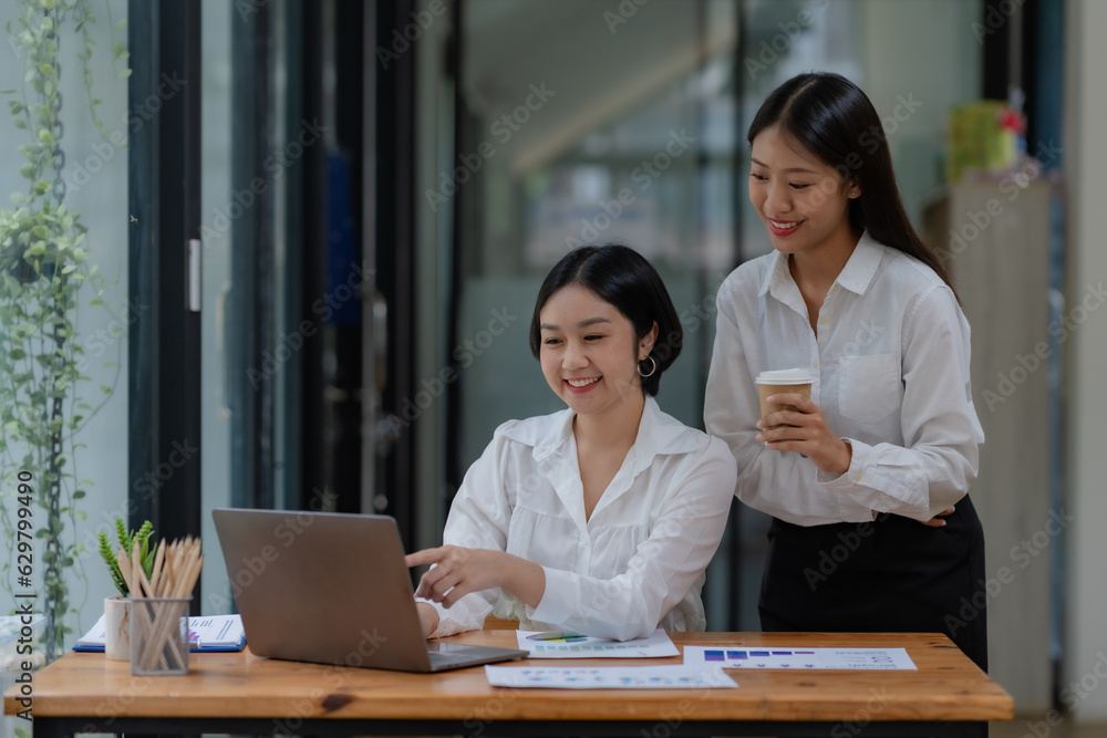 Obraz premium Two young Asian businesswoman consult and talk analysis of marketing planning with laptop computer.